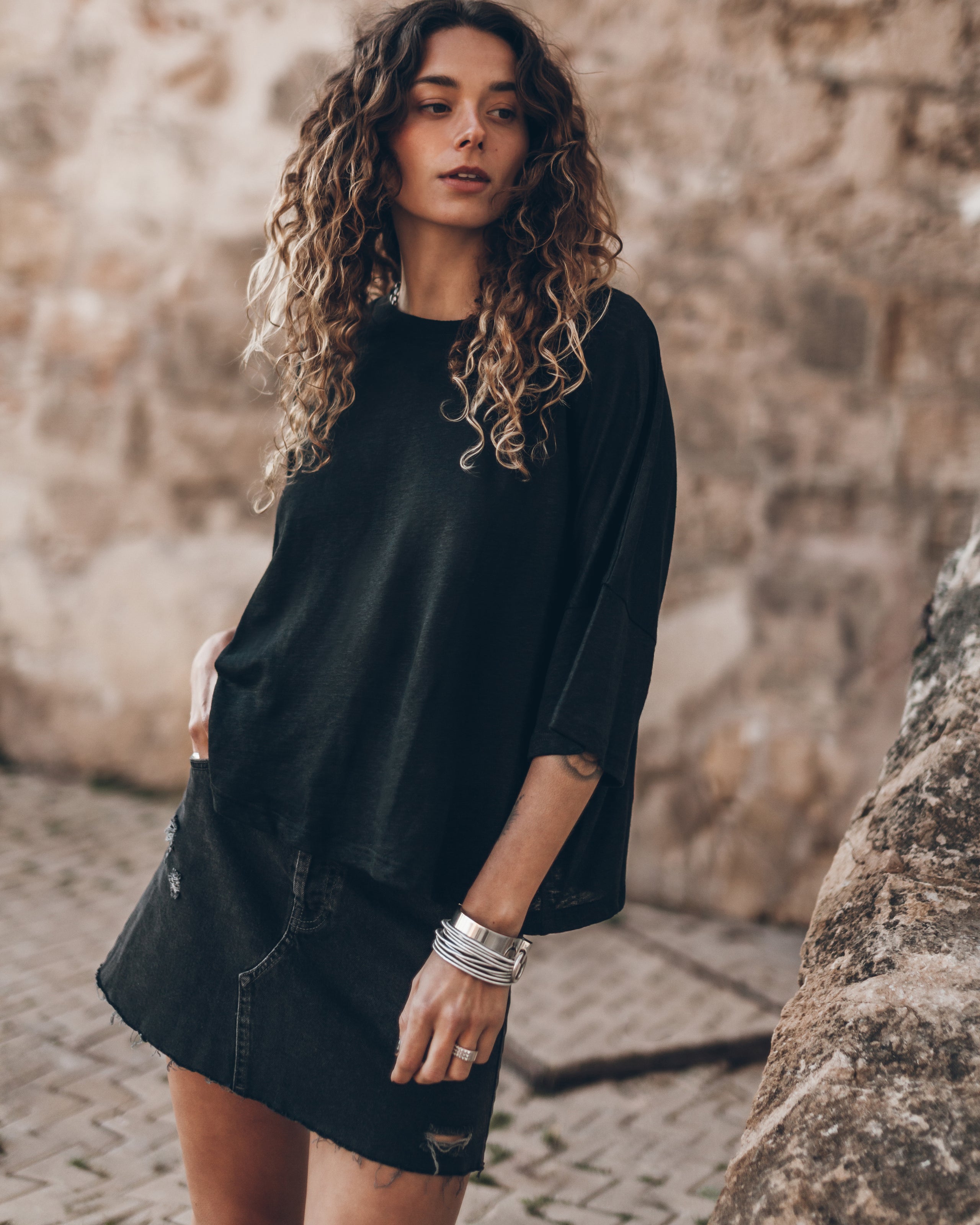 Black loose-fit linen t-shirt with three-quarter sleeves worn with matching black skirt.