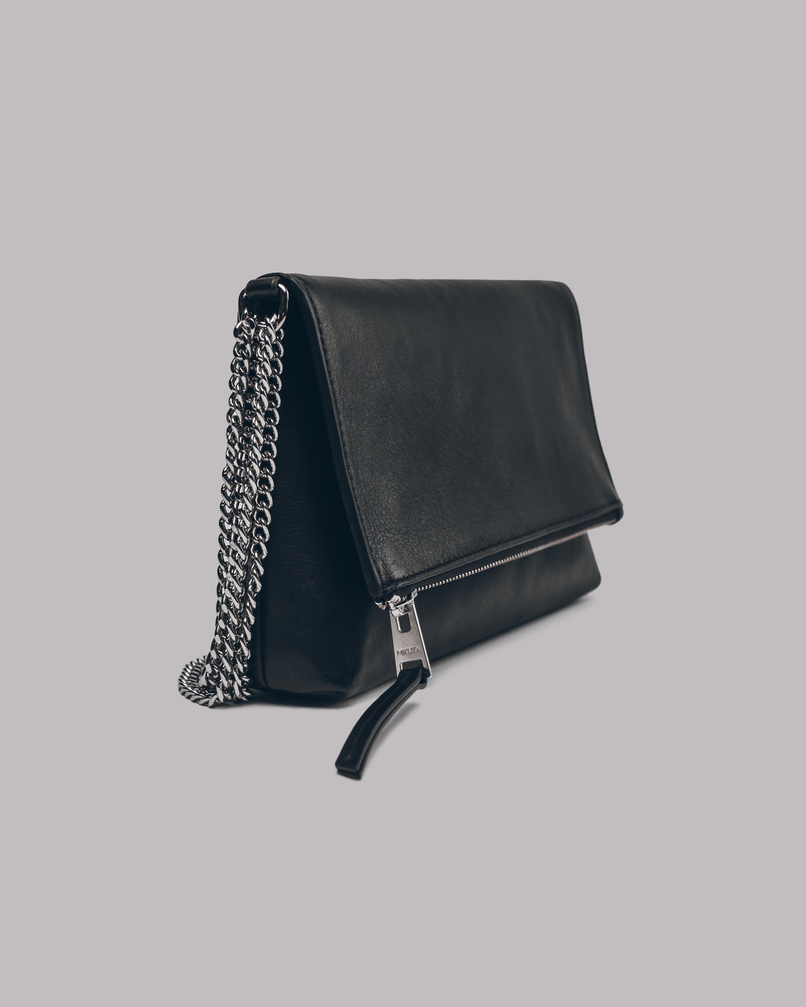 Black leather handbag with a chain detail on a gray background