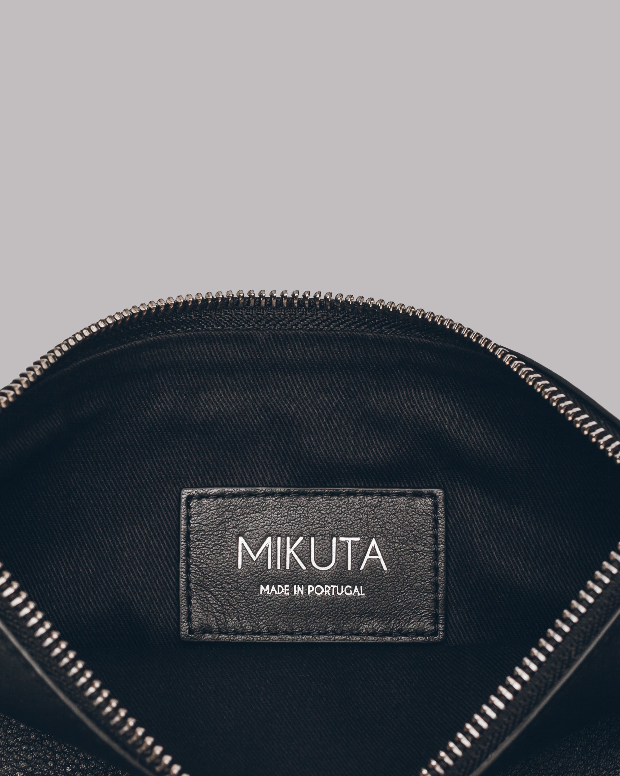 Black pouch with 'MIKUTA' brand label on a black leather clutch bag