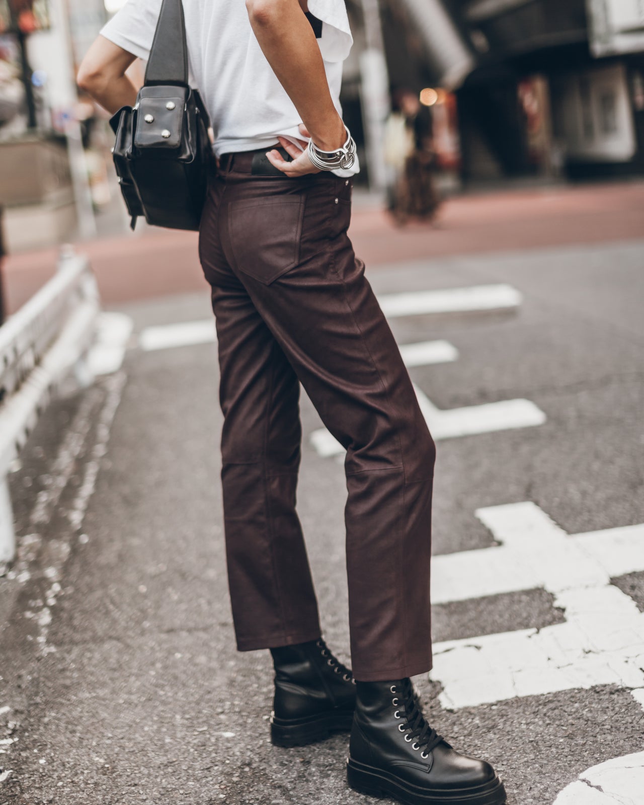 Person wearing brown pants and black boots on a city street.