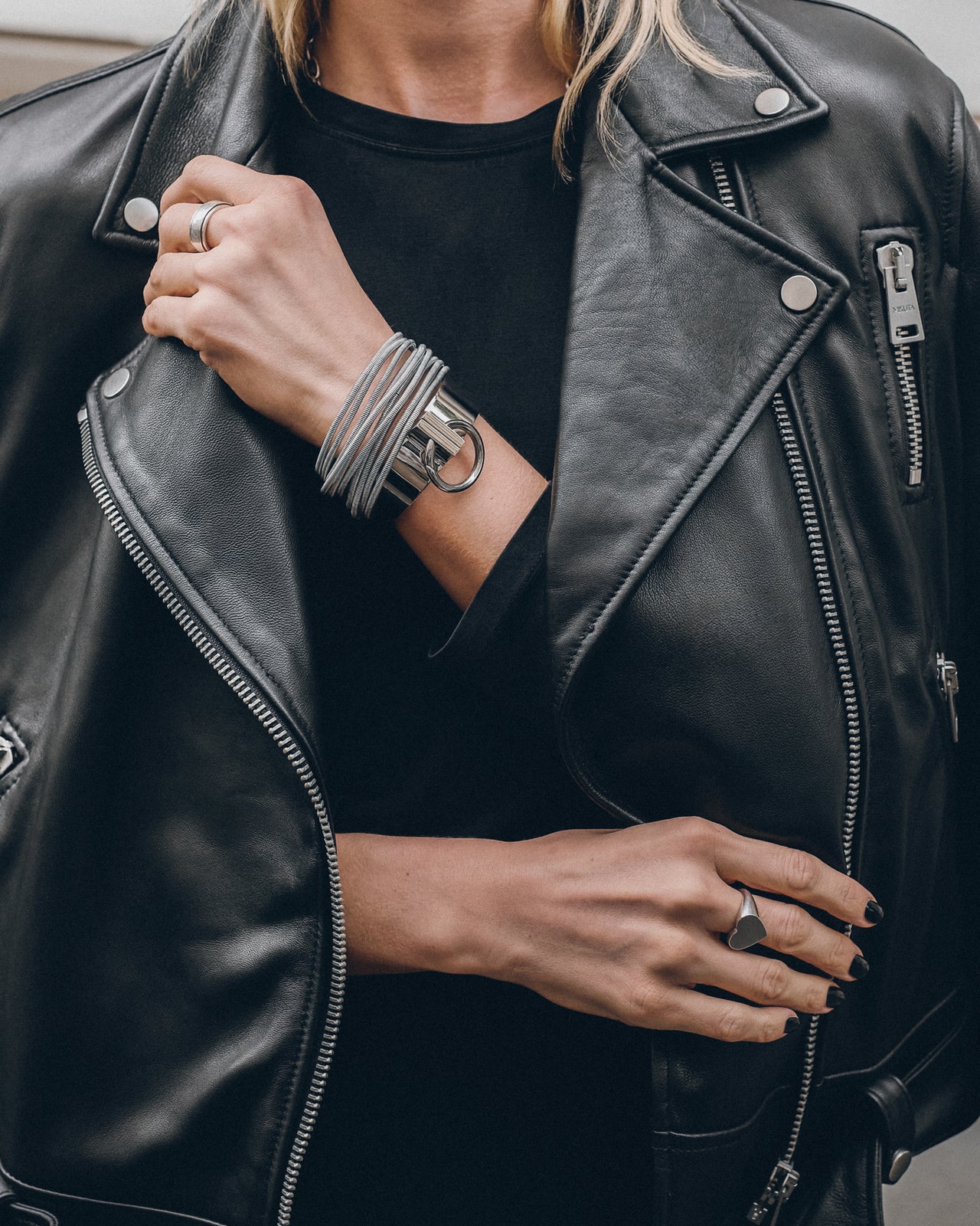 Person wearing a black leather jacket with visible jewelry