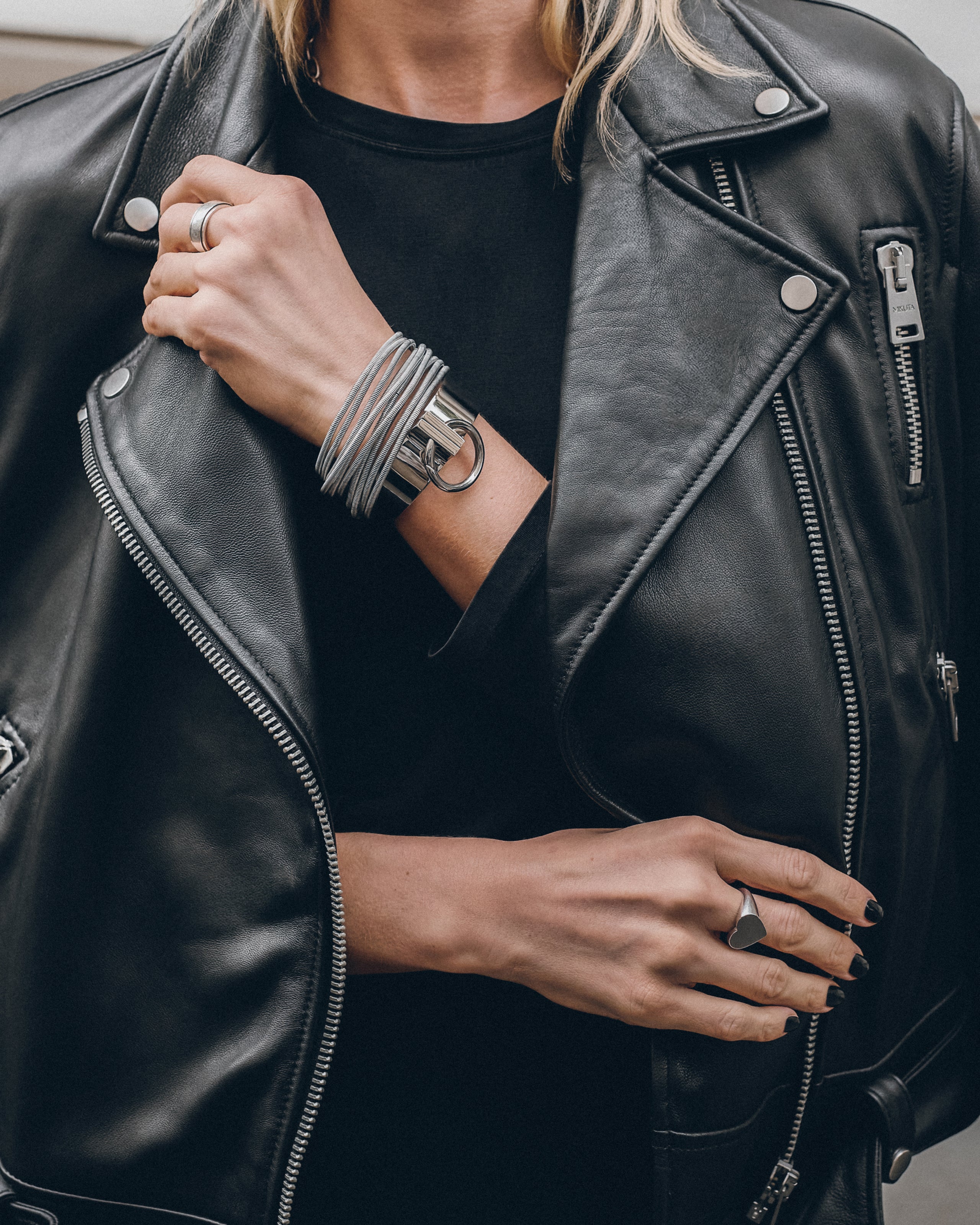 Person wearing a black leather jacket with visible jewelry