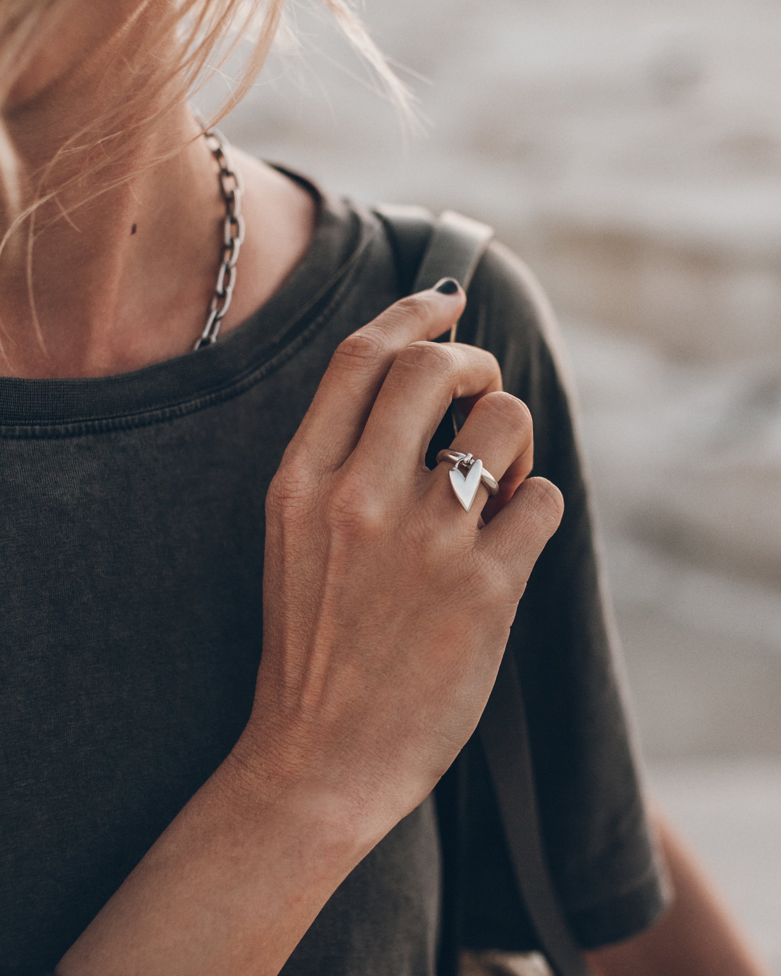 Person wearing a black shirt and a silver ring with a heart charm.