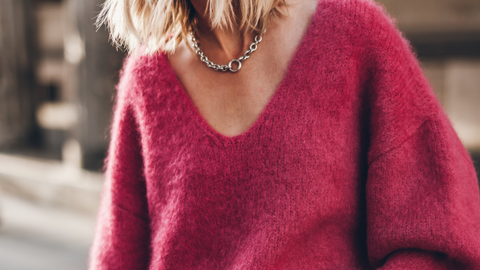 Person wearing a pink sweater with a blurred background