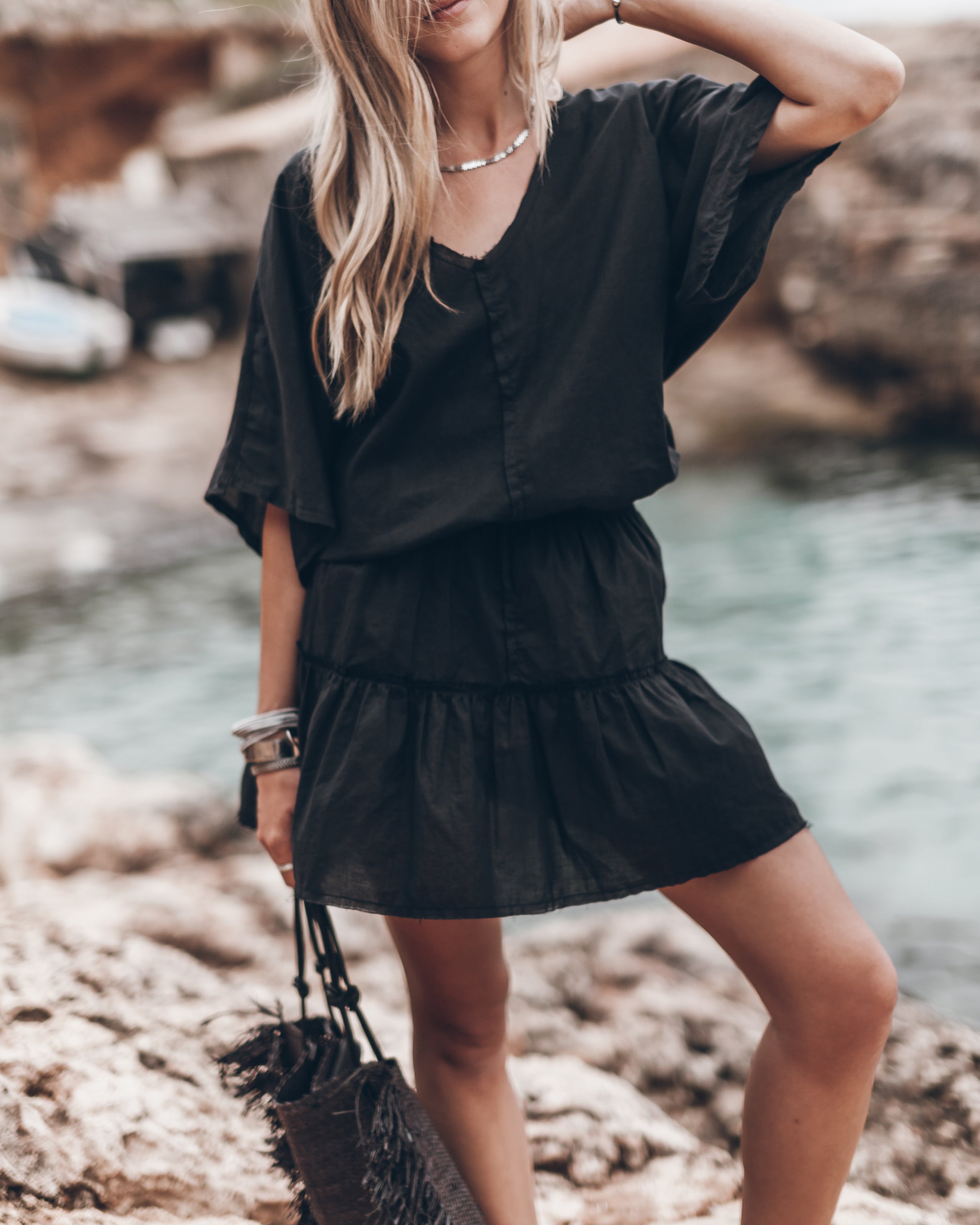 Black short-sleeve V-neck summer dress with tiered ruffle hem and relaxed fit.