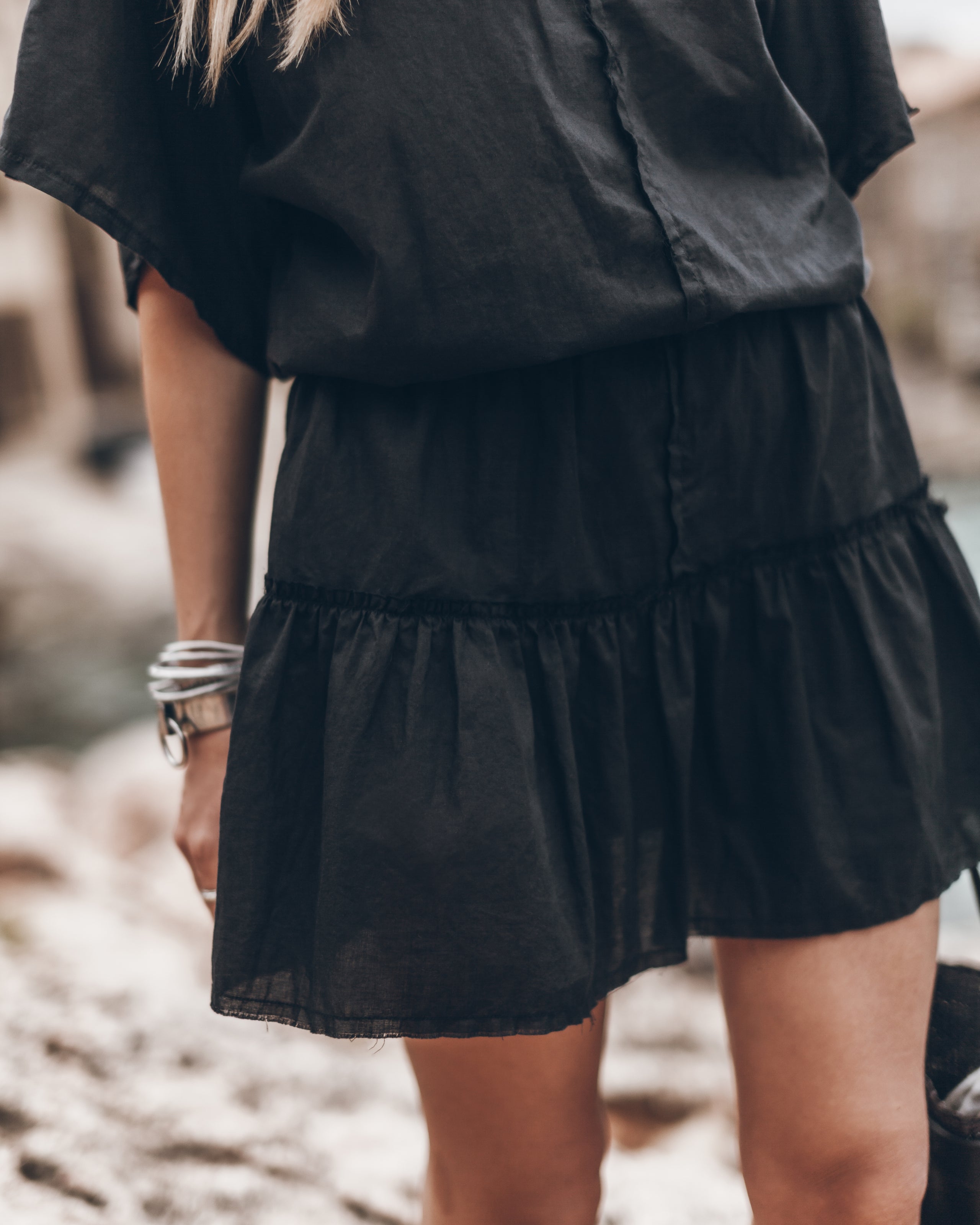 Black short-sleeve mini dress with tiered skirt and button-up front detail.