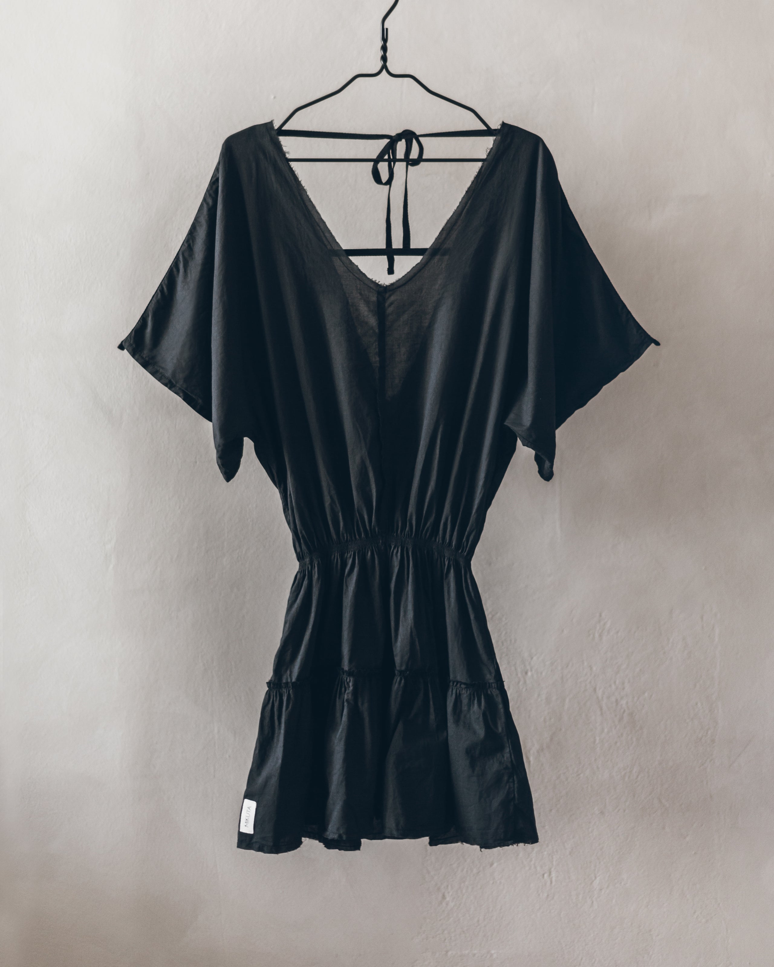 Black short-sleeve summer dress with V-neck, cinched waist, and tiered ruffle hem.