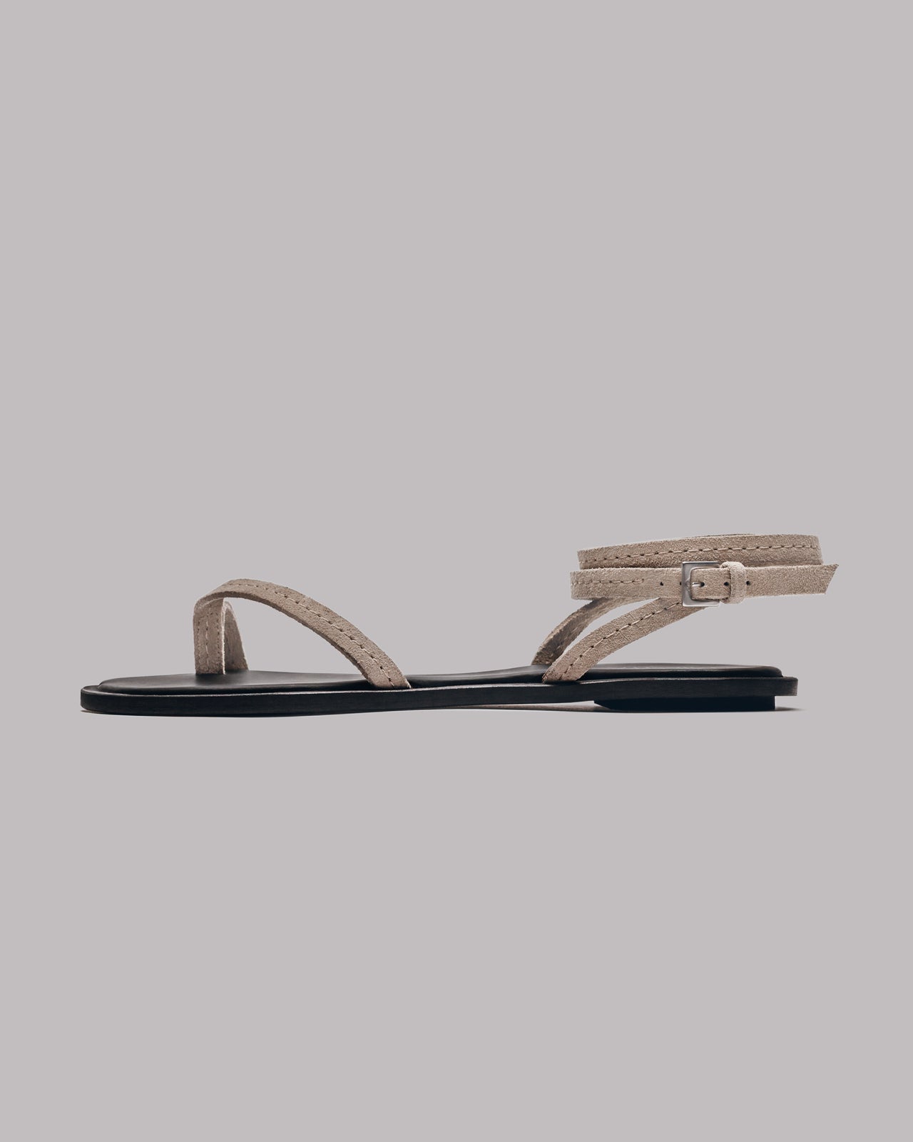 Beige sandal with a black sole on a gray background