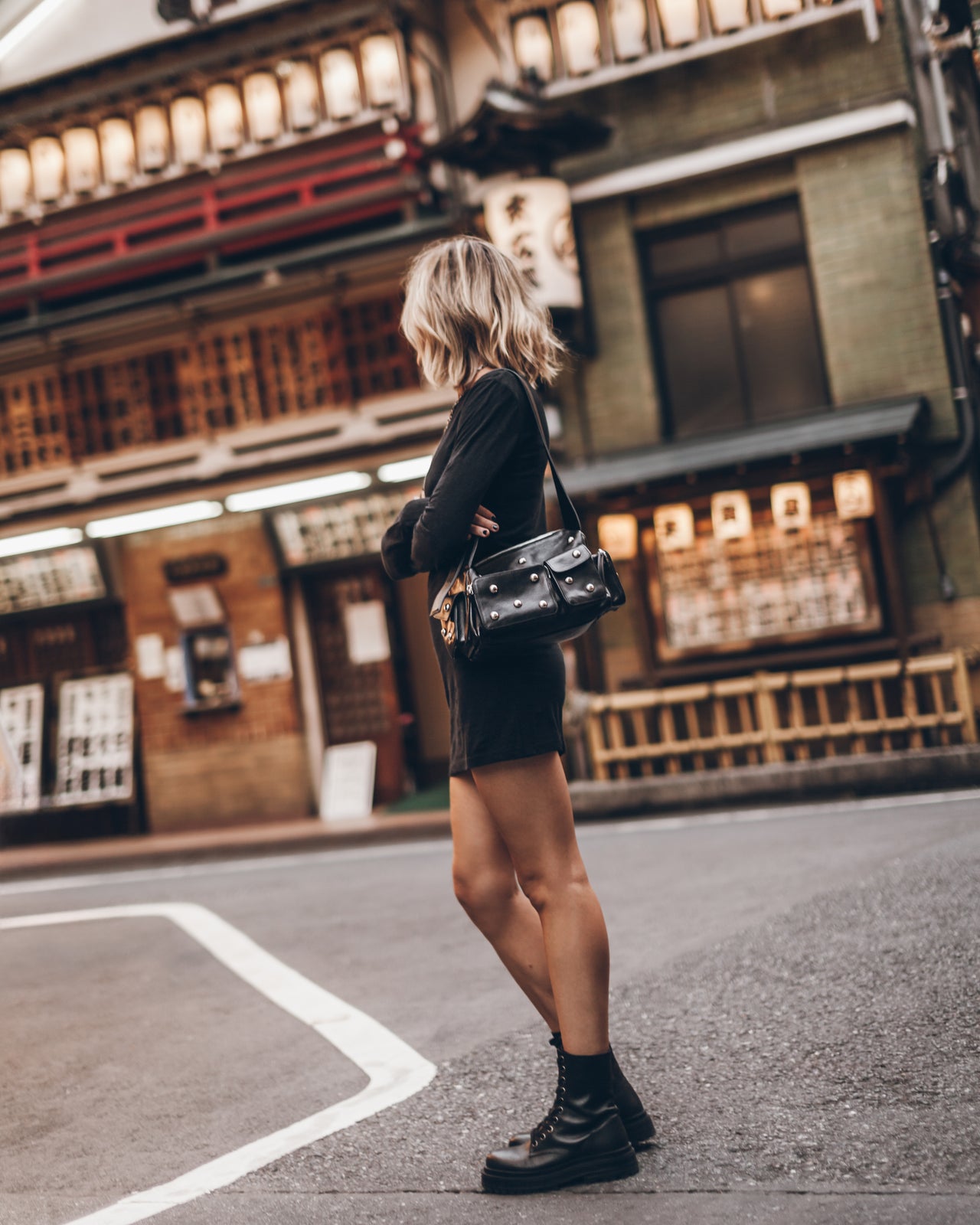 Woman walking on a street in an urban setting with traditional architecture.
