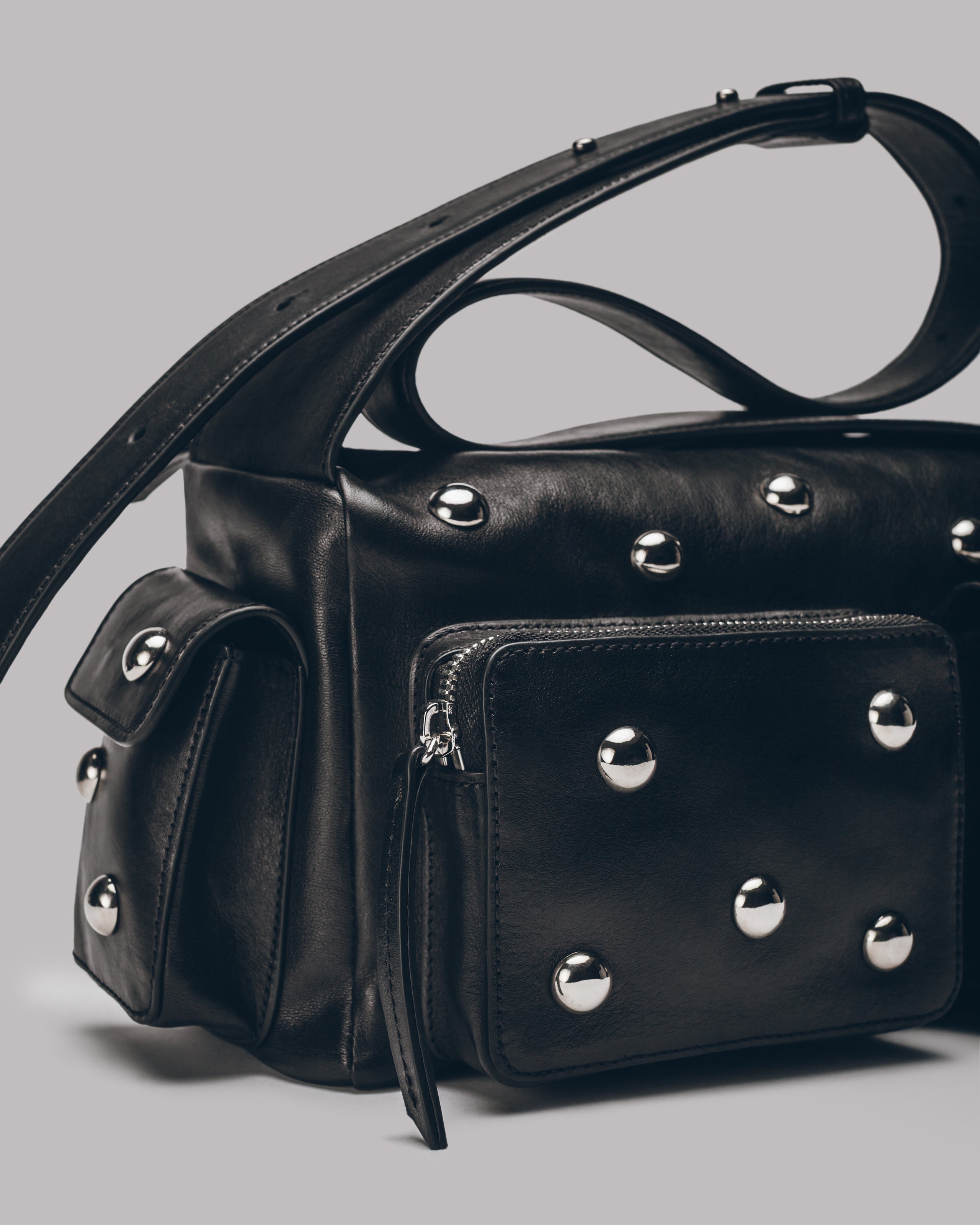 Black handbag with silver studs on a gray background