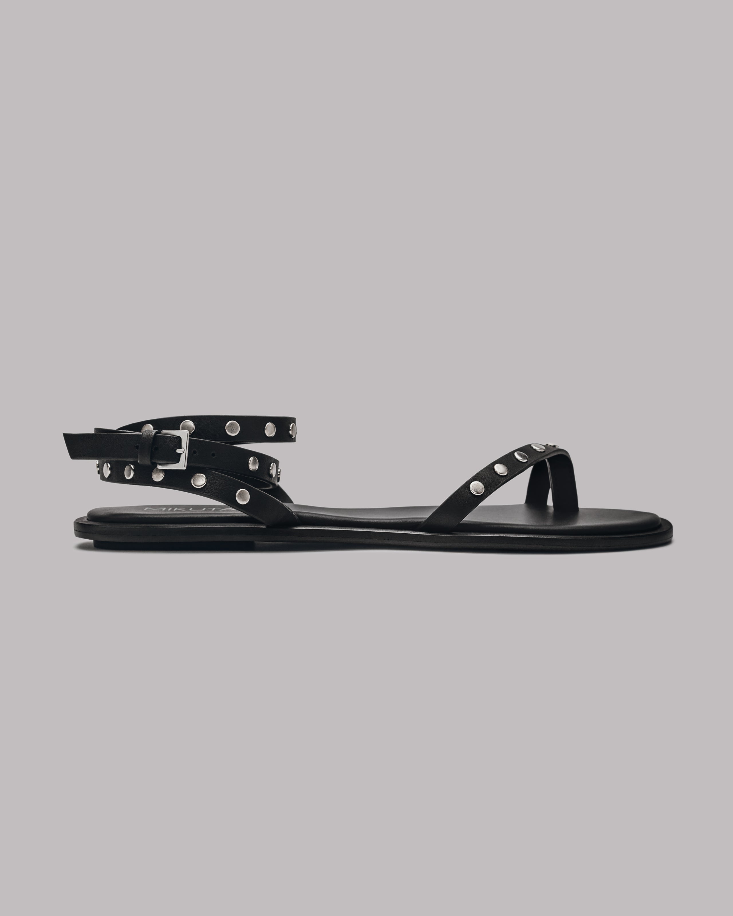 Black studded sandal with a black sole on a gray background