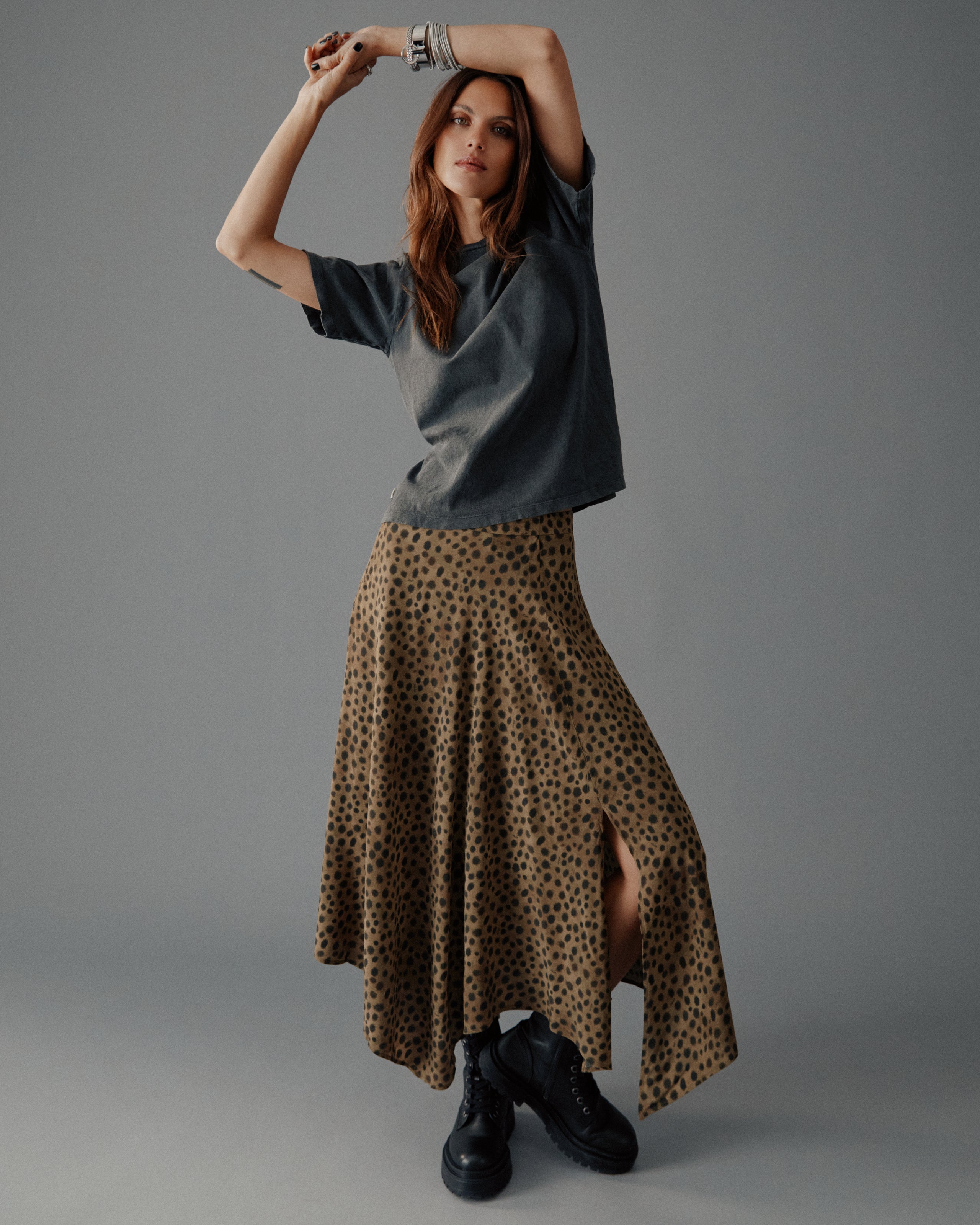 Woman wearing a gray top and leopard print skirt on a gray background