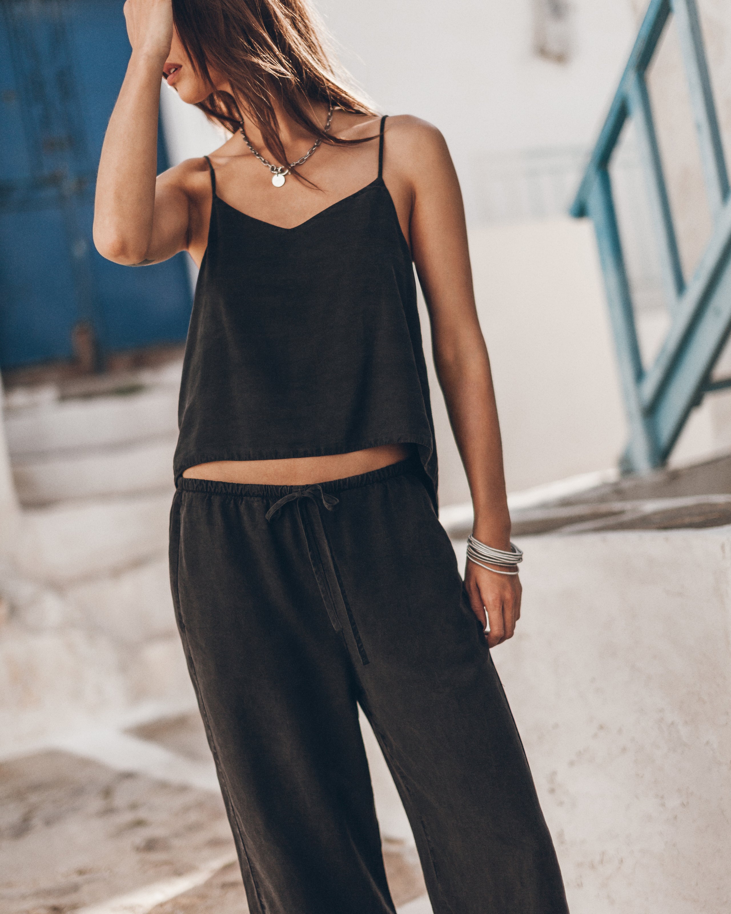 Woman wearing a black sleeveless top and pants in an urban setting