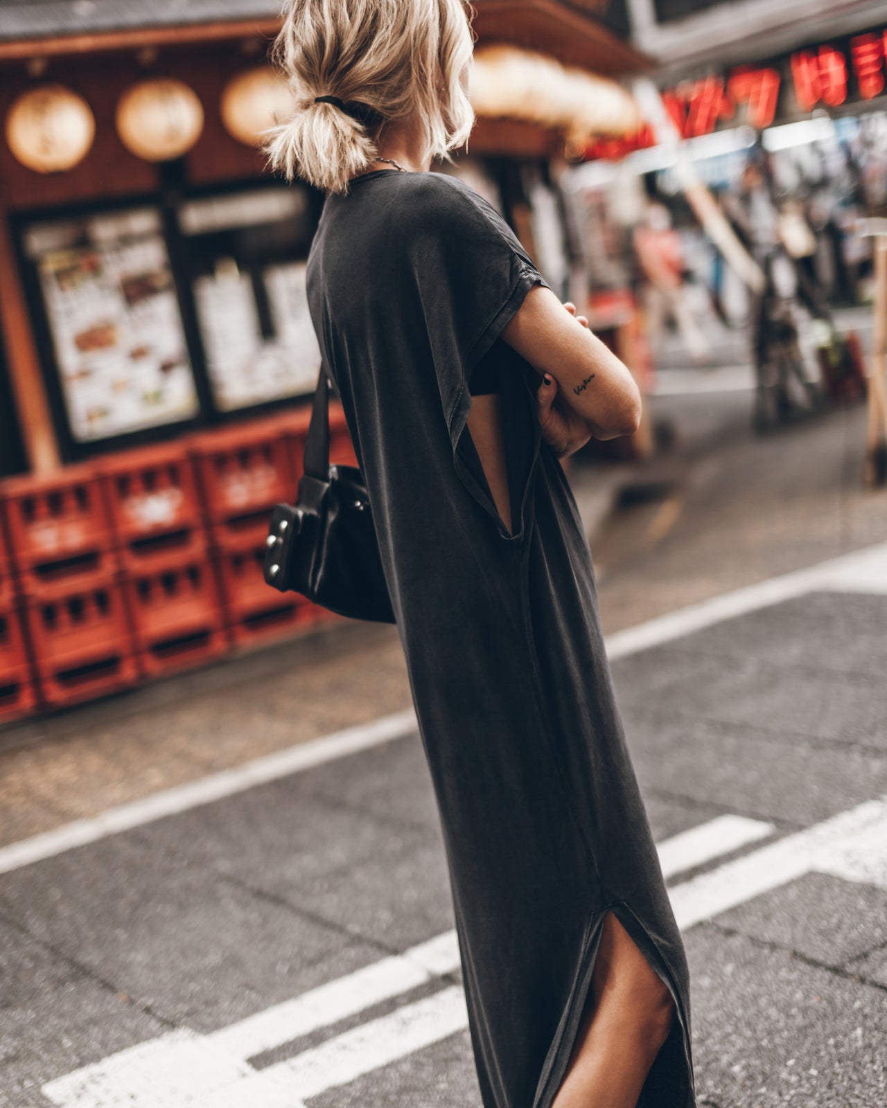 Woman in a long black dress walking on a street with a blurred background
