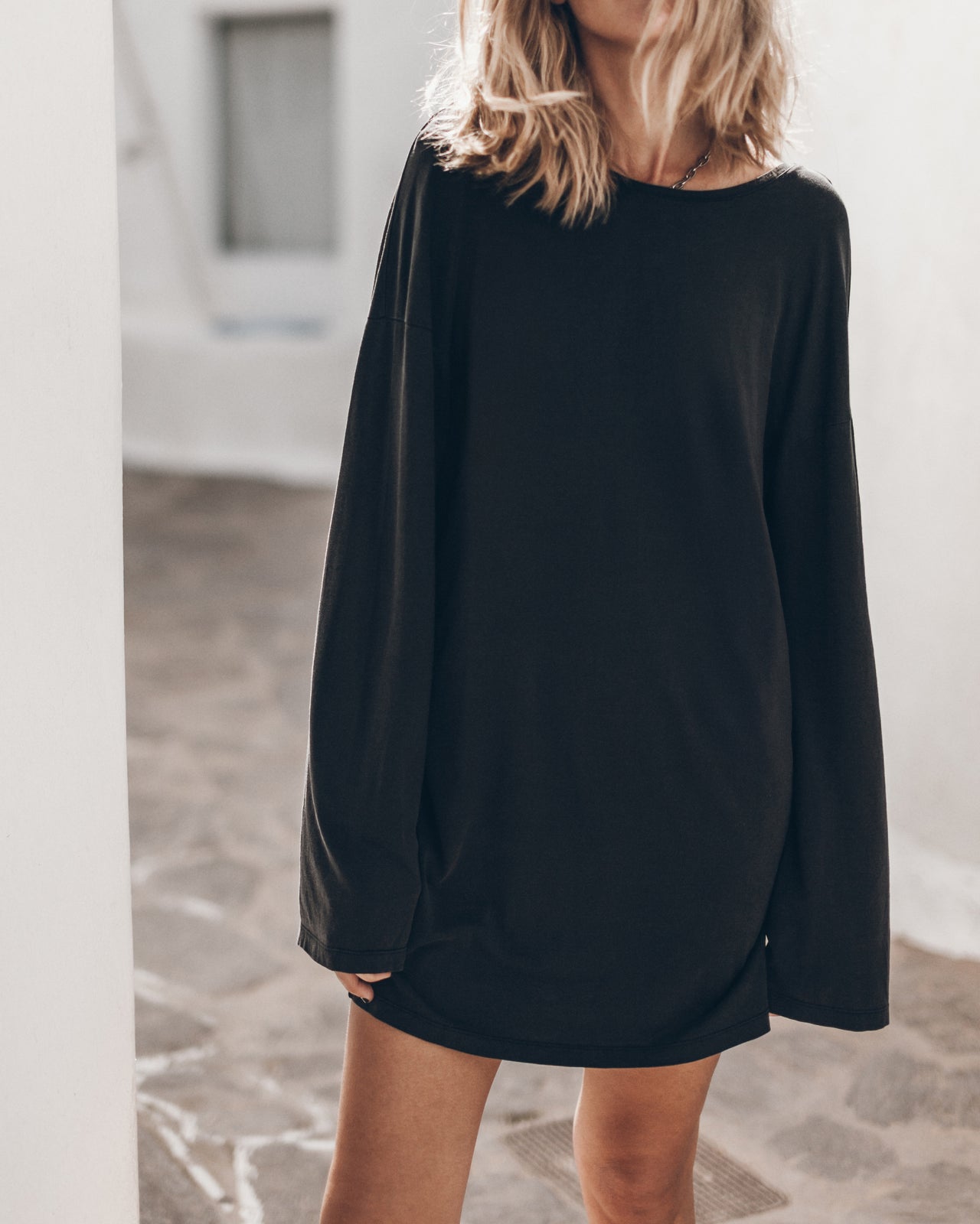 Woman wearing a black long-sleeve dress in an indoor setting.