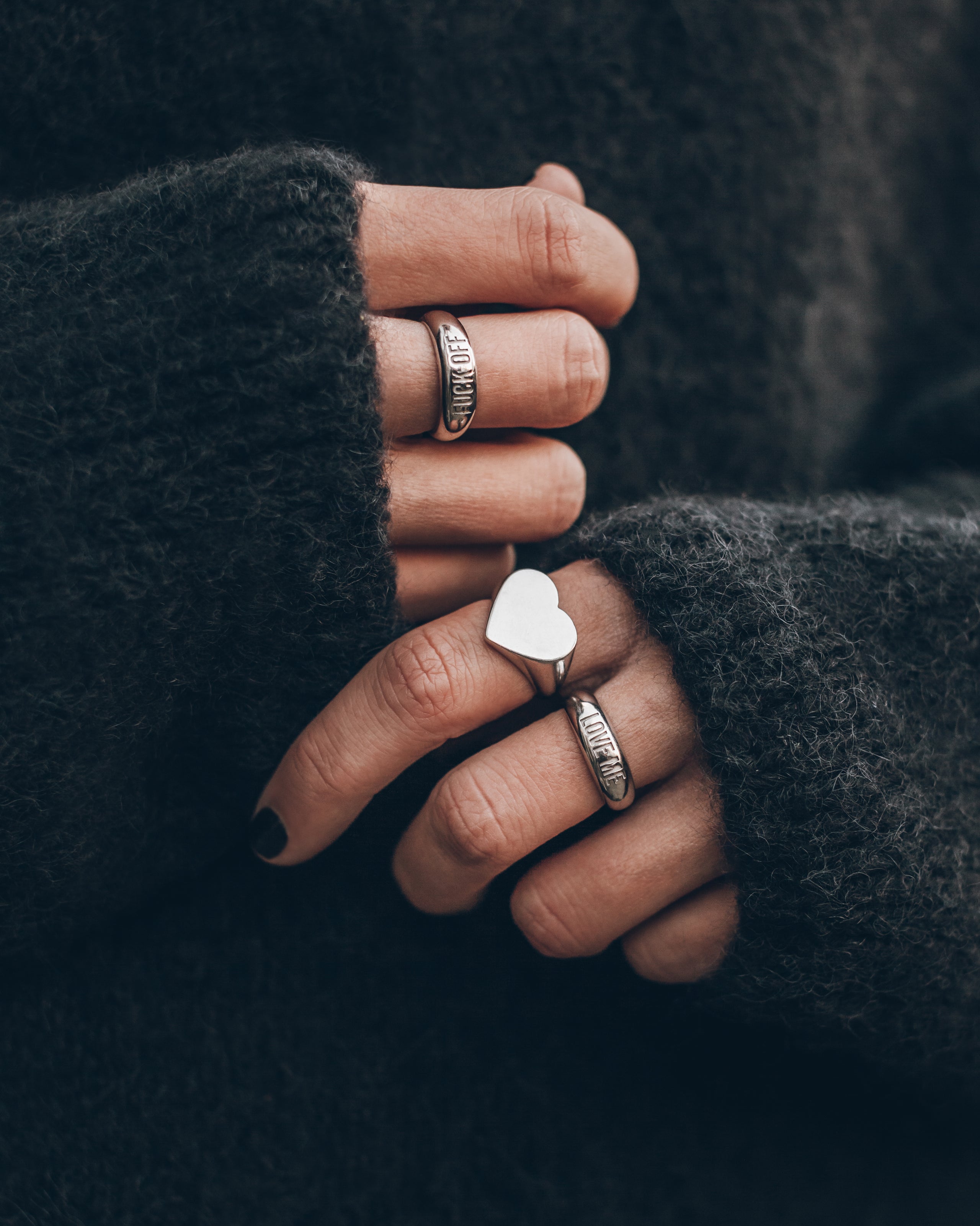 Hand wearing multiple rings with a dark background
