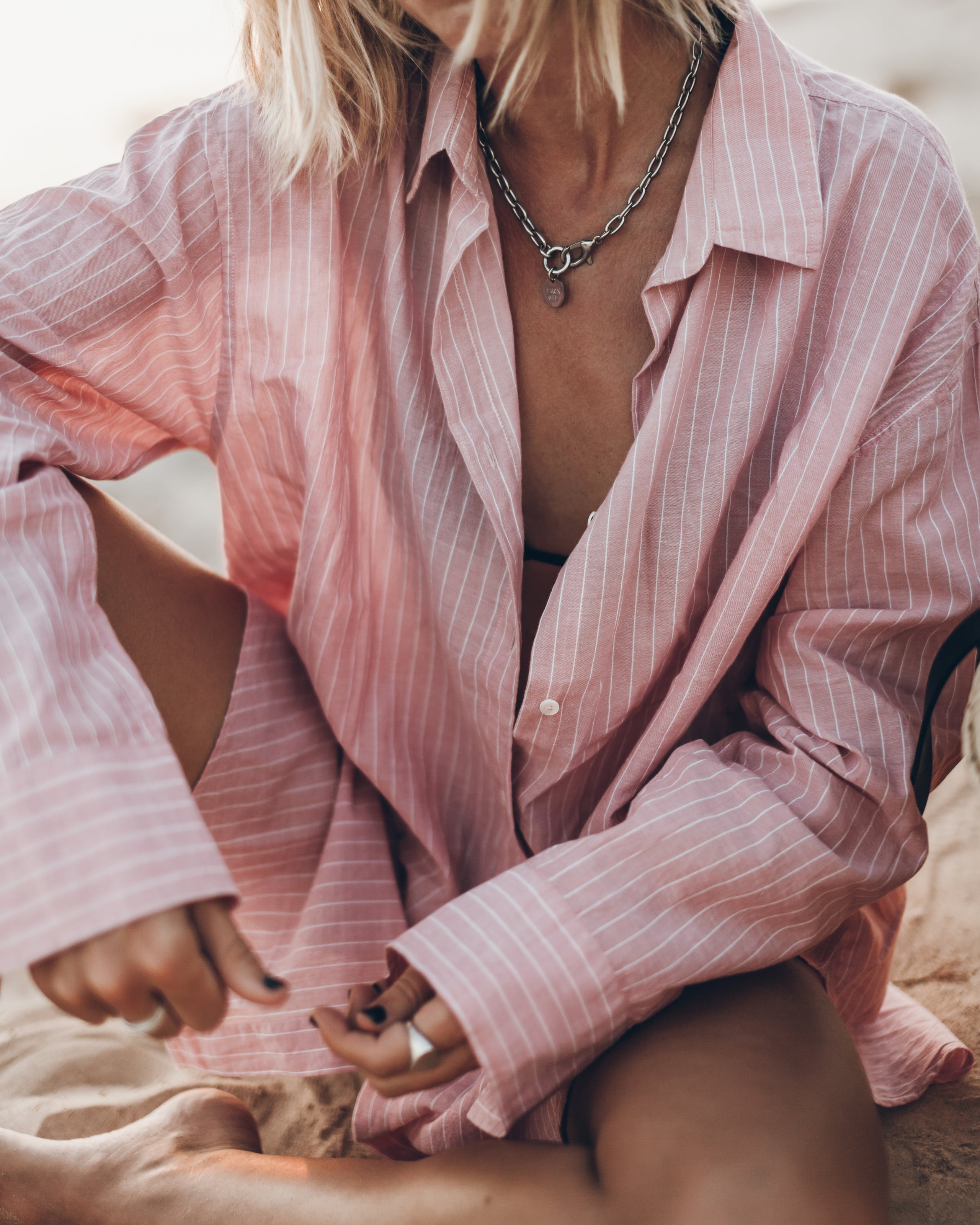 Person wearing a pink striped shirt with a blurred background