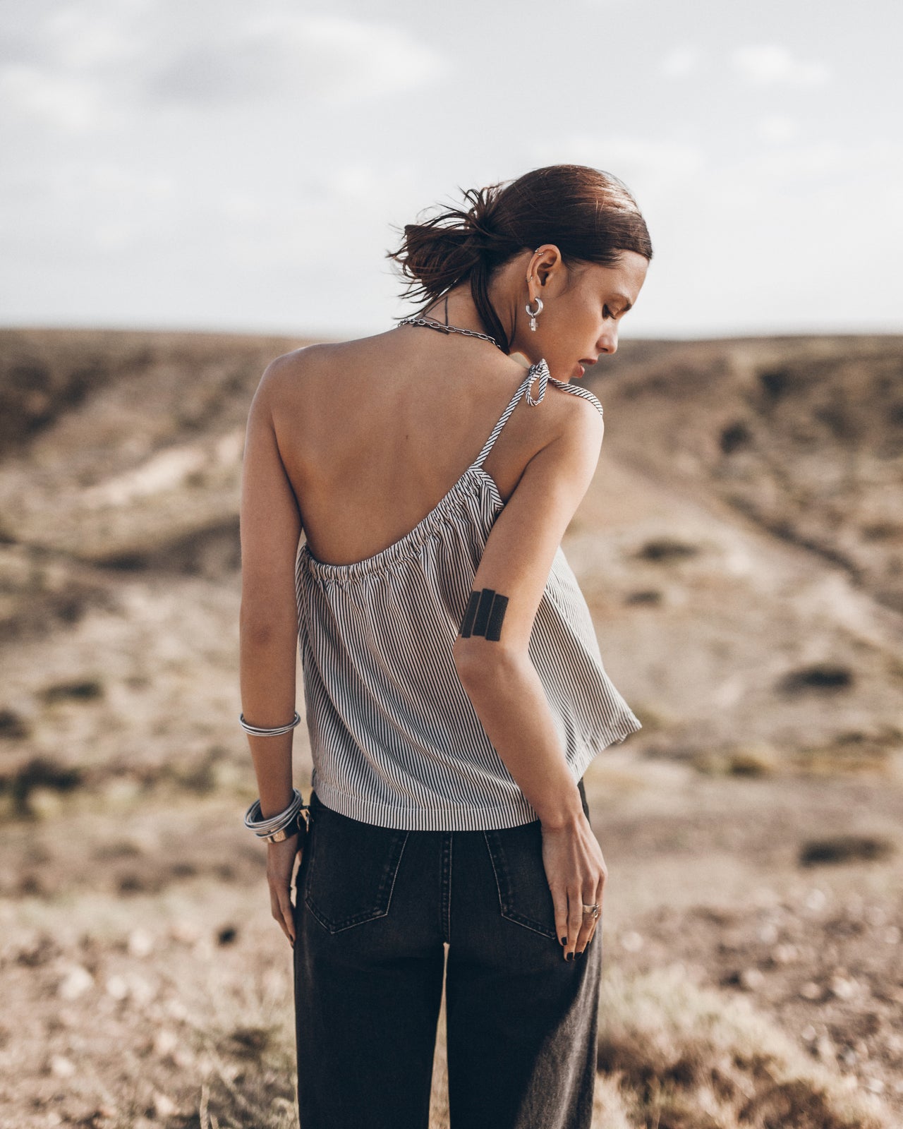 Woman in a striped top and dark pants standing in a desert landscape