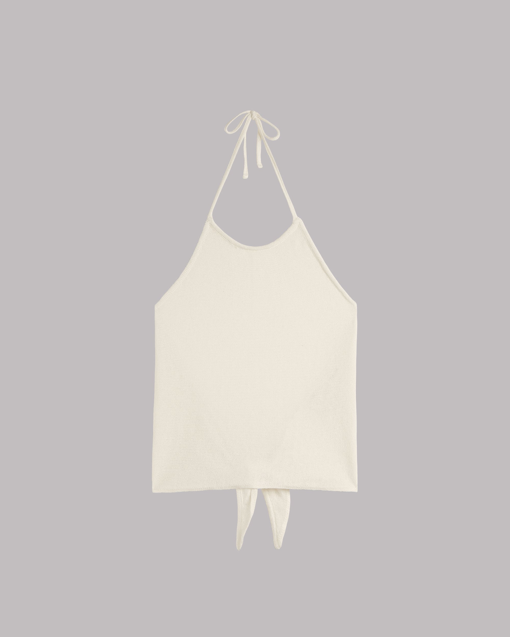 White halter top with back tie details on a gray background.
