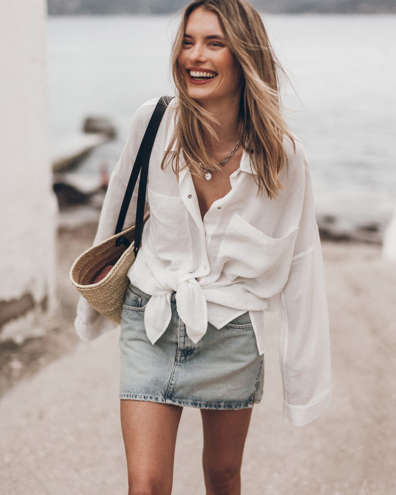Woman wearing a white blouse and denim skirt by a waterfront