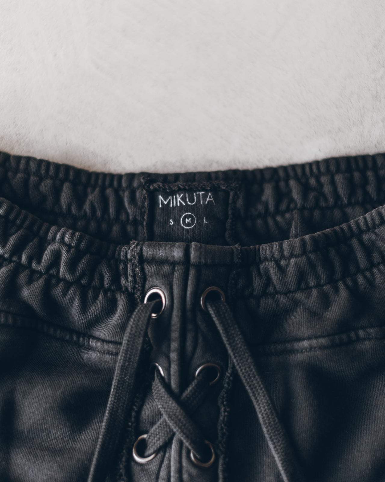 Charcoal elastic waistband shorts with black drawstring laces and Mikuta brand label.