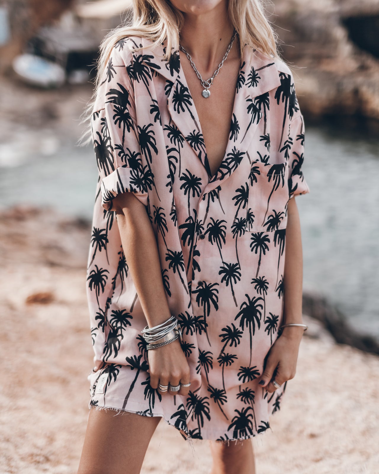 Light pink button-up shirt with black palm tree print and rolled-up sleeves.