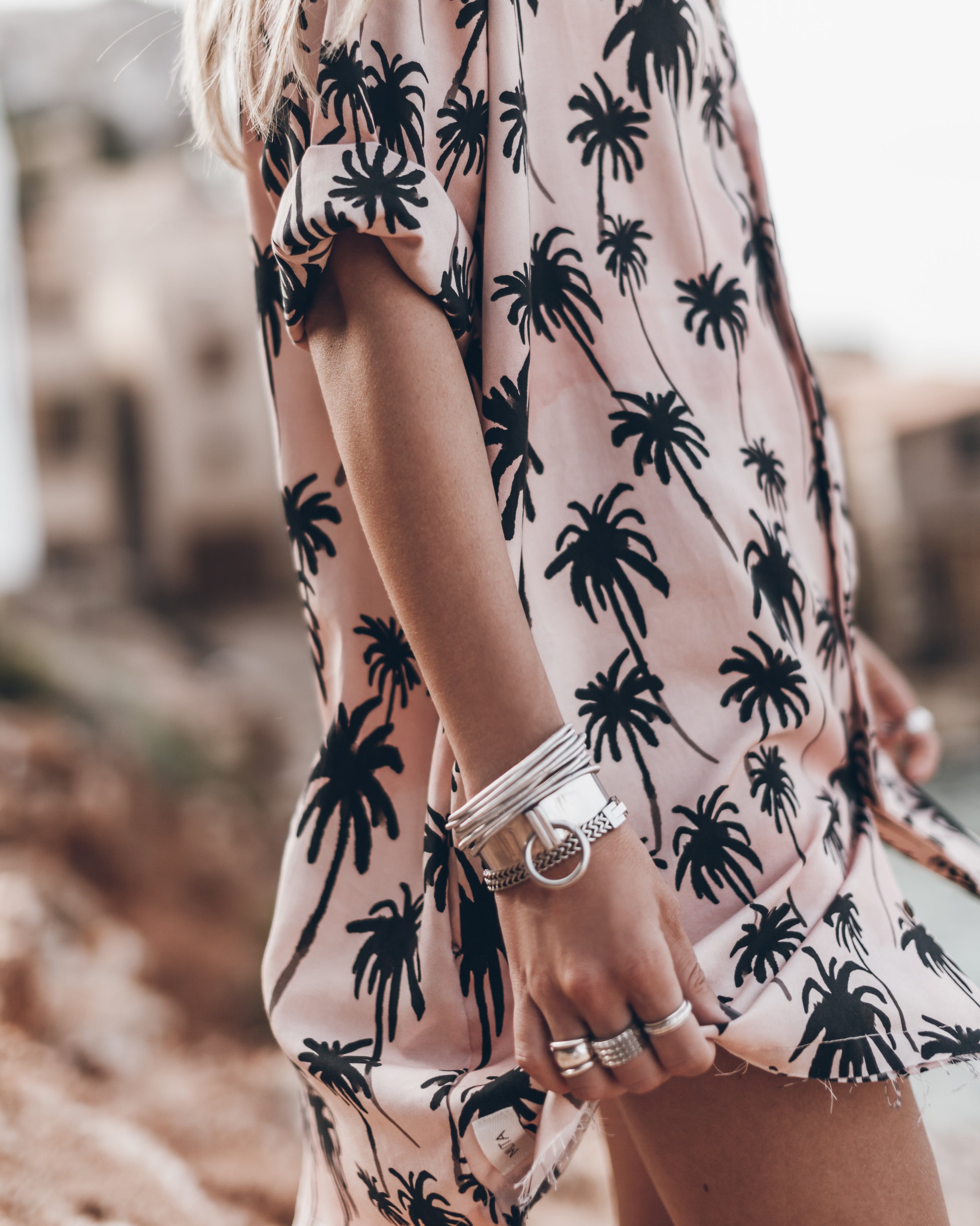 Light pink short-sleeve shirt with black palm tree print and side slit hem.