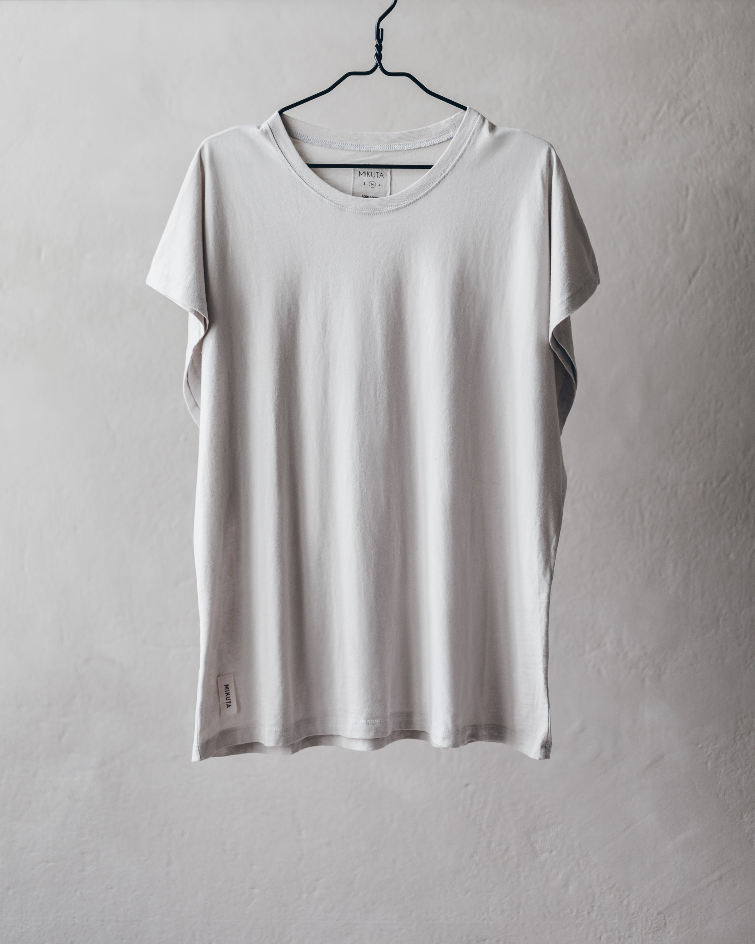 Light gray short-sleeve crew neck t-shirt with relaxed fit hanging on black hanger.