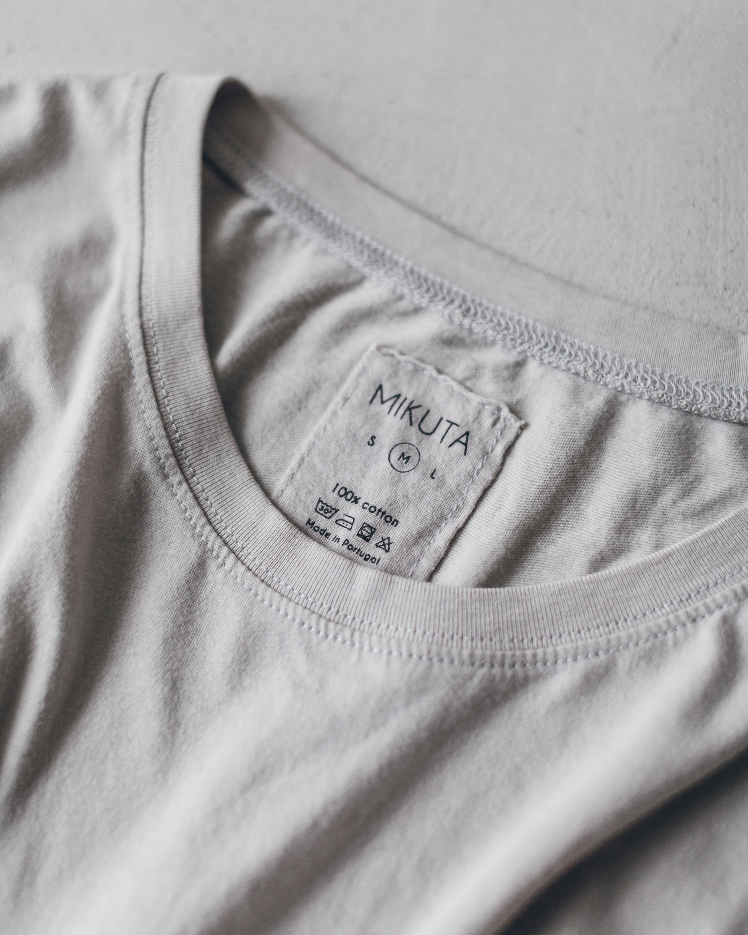 Light gray cotton t-shirt with round neckline and visible brand tag inside collar.