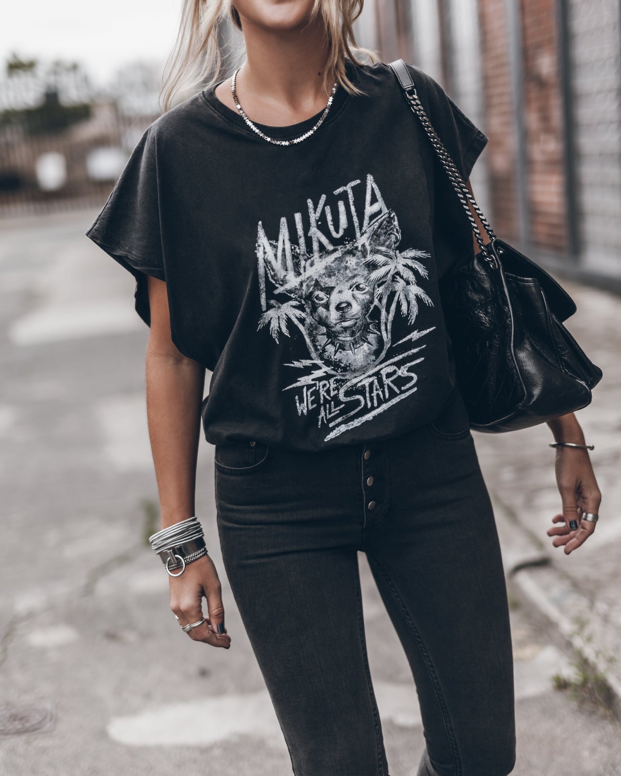 Black oversized t-shirt with white graphic print and text, paired with black high-waisted jeans.